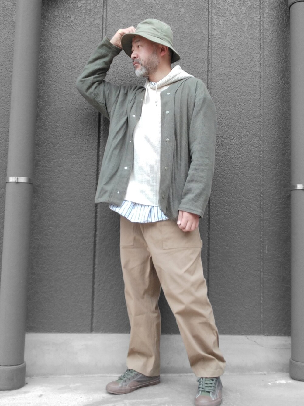 ベージュ系のパンツ、グリーン系のスニーカー、ベージュ系のパーカーを着用したメンズの春コーディネートの1枚目の写真