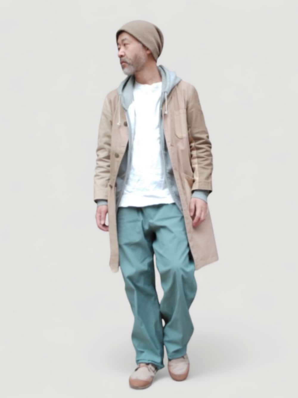 グリーン系のパンツ、ベージュ系のスニーカー、ベージュ系のステンカラーコートを着用したメンズの冬コーディネートの1枚目の写真