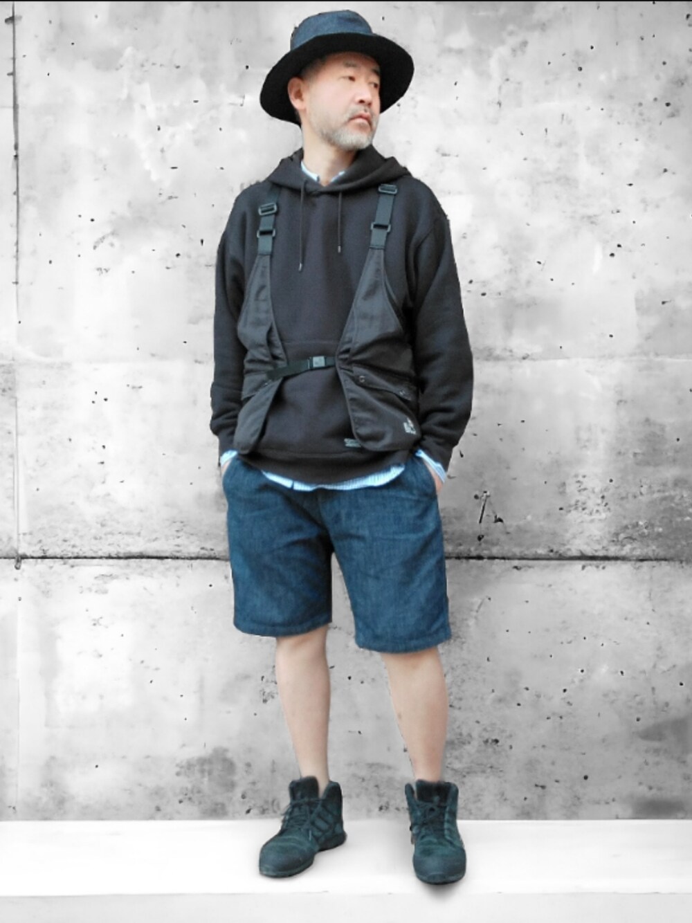 ブラック系のベスト、ブルー系のデニムパンツ、ブラック系のスニーカーを着用したメンズの春コーディネートの1枚目の写真