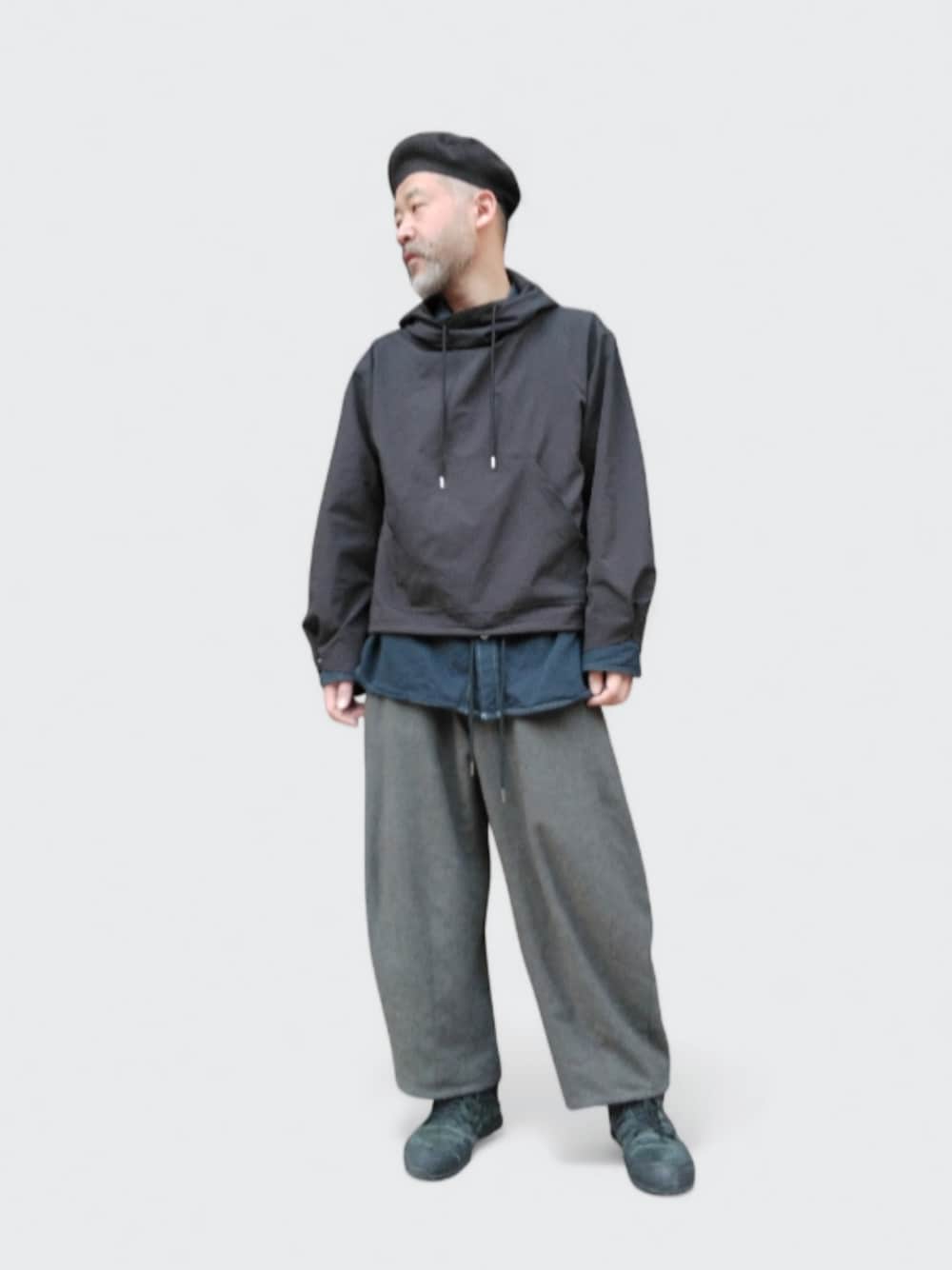 グレー系のパンツ、ブラック系のパーカー、ブラック系のハンチング/ベレー帽を着用したメンズの冬コーディネートの1枚目の写真