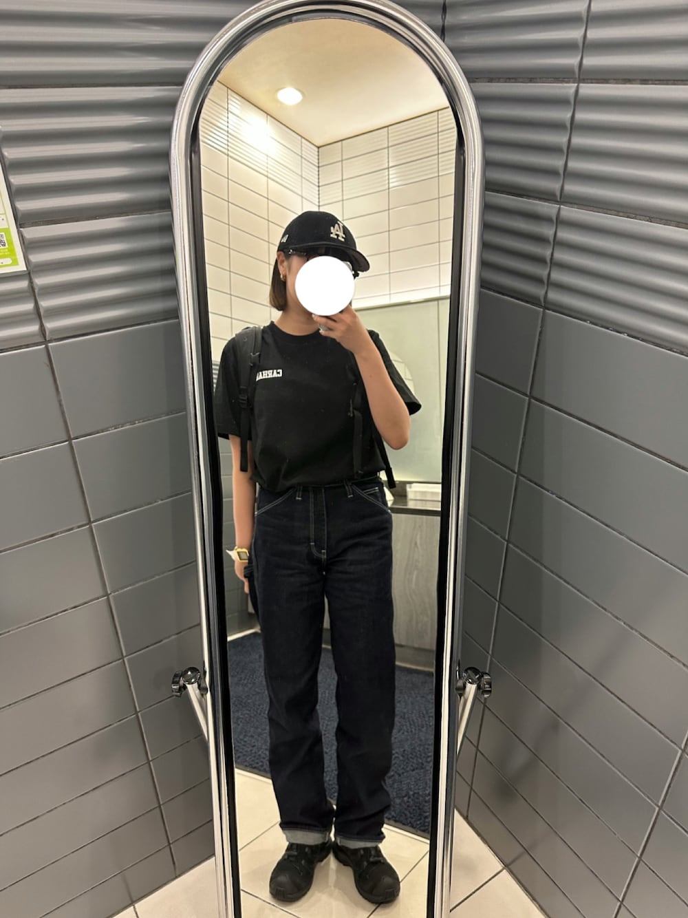 ブルー系のデニムパンツ、ブラック系のTシャツ/カットソー、ブラック系のスニーカーを着用したレディースの冬コーディネートの1枚目の写真