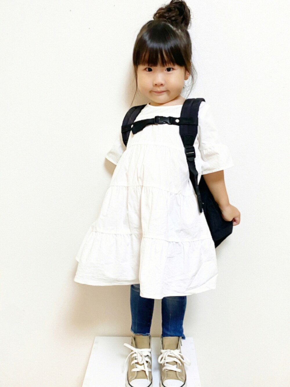 ホワイト系のワンピース、ブルー系のデニムパンツ、ベージュ系のスニーカーを着用したキッズの夏コーディネートの1枚目の写真