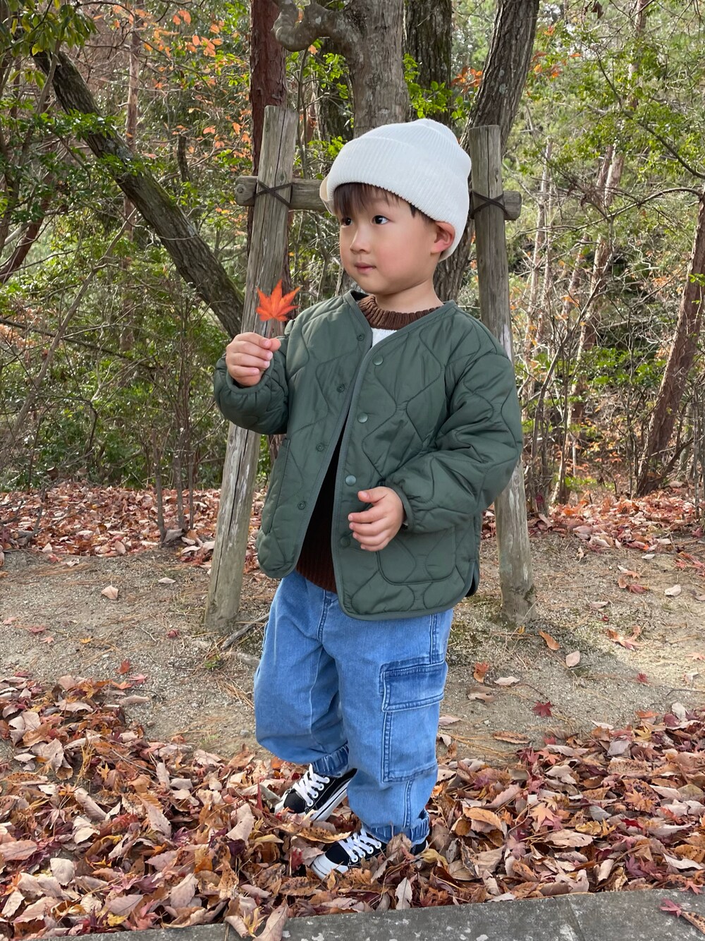 ブラウン系のニット/セーター、グリーン系のノーカラージャケット、ブルー系のカーゴパンツを着用したキッズの冬コーディネートの1枚目の写真