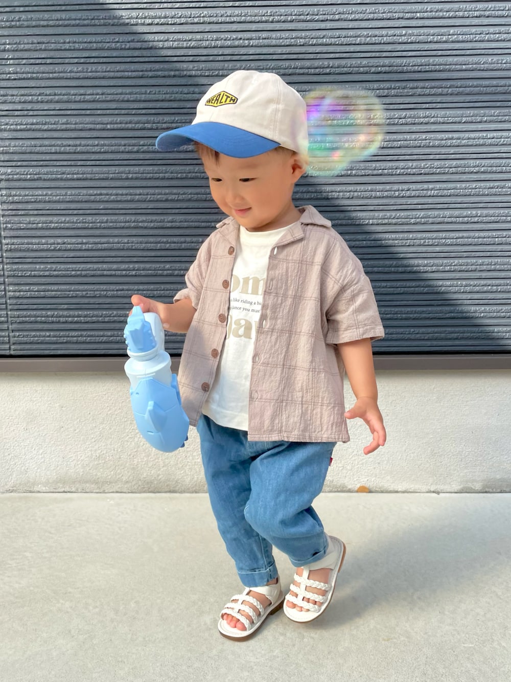 ベージュ系のセットアップ、ベージュ系のTシャツ/カットソー、ブルー系のデニムパンツを着用したキッズの夏コーディネートの1枚目の写真