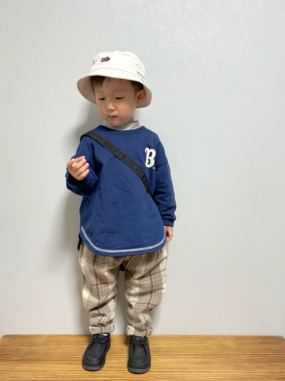 グリーン系のスウェット、ブラック系のブーツ、ブラック系のショルダーバッグを着用したキッズの春コーディネートの1枚目の写真