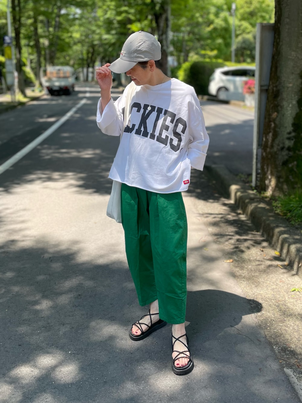 ホワイト系のTシャツ/カットソー、ブラック系のサンダル、グリーン系のチノパンツを着用したレディースの夏コーディネートの1枚目の写真