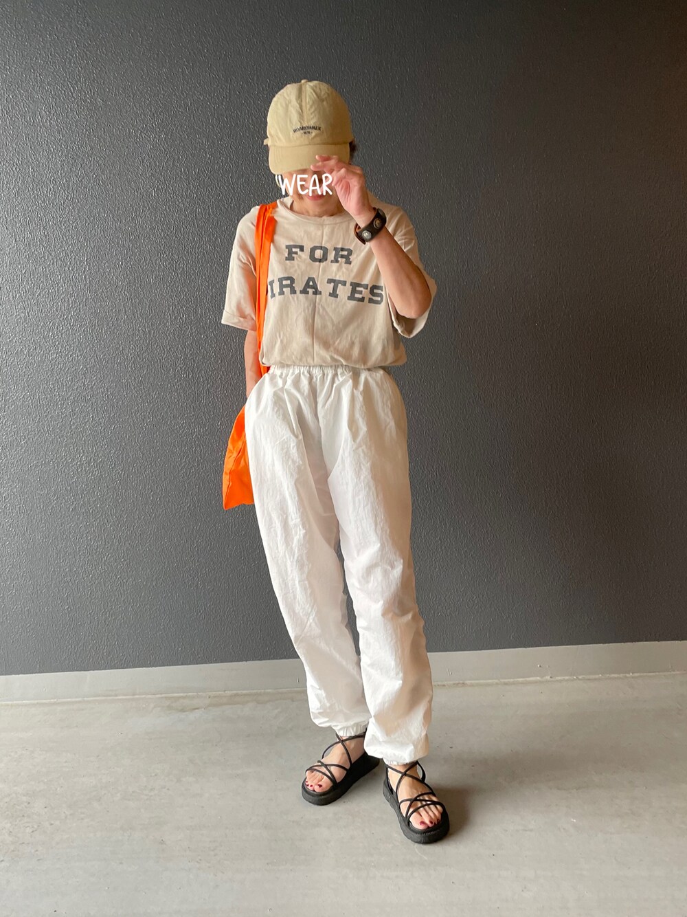 ホワイト系のその他パンツ、ブラック系のサンダル、オレンジ系のハンドバッグを着用したレディースの夏コーディネートの1枚目の写真