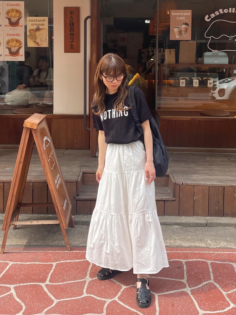 ホワイト系のスカート、ブラック系のその他シューズを着用したレディースの春コーディネートの1枚目の写真