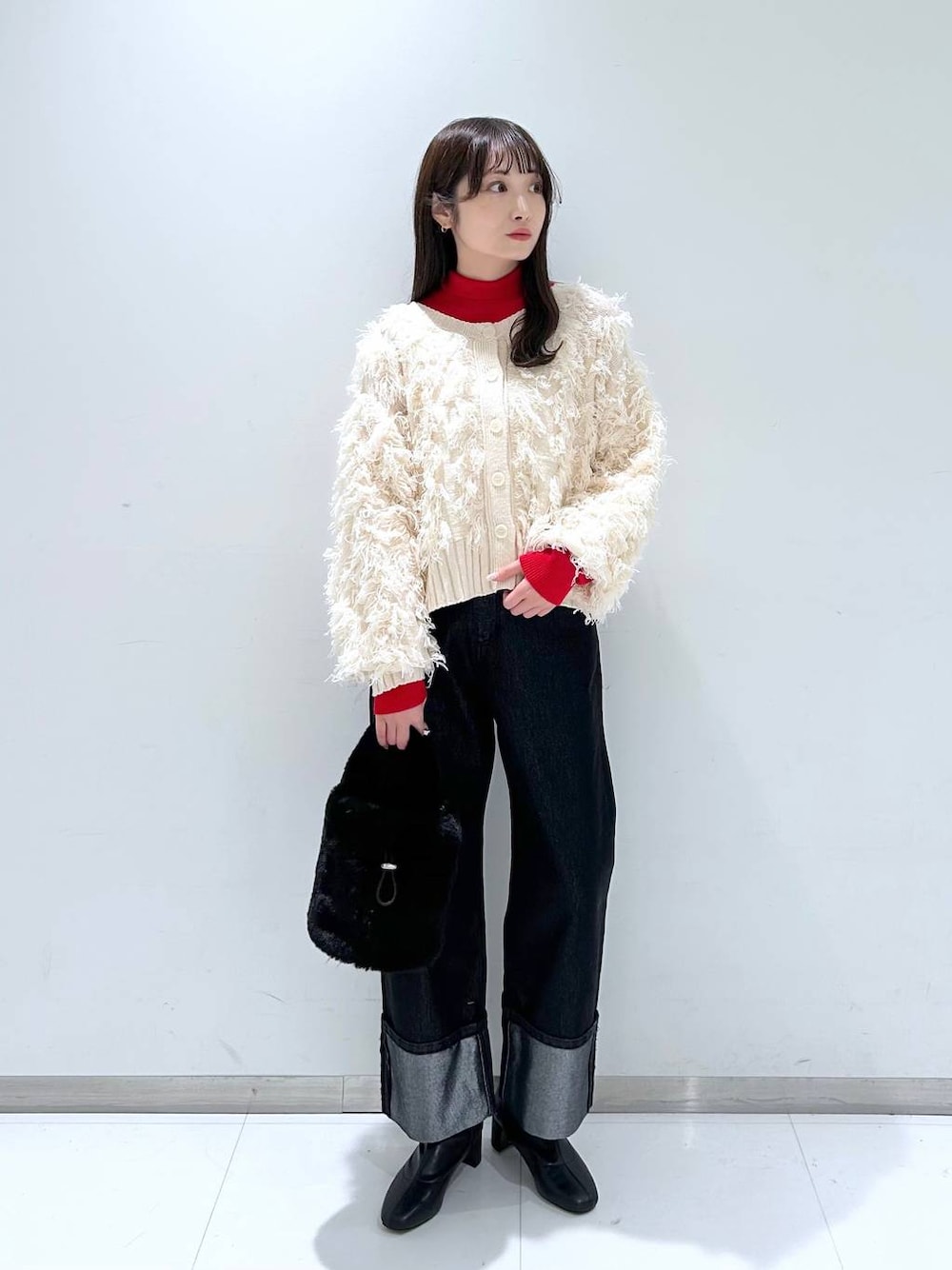 レッド系のニット/セーター、ブラック系のブーツ、ブラック系のショルダーバッグを着用したレディースの冬コーディネートの1枚目の写真