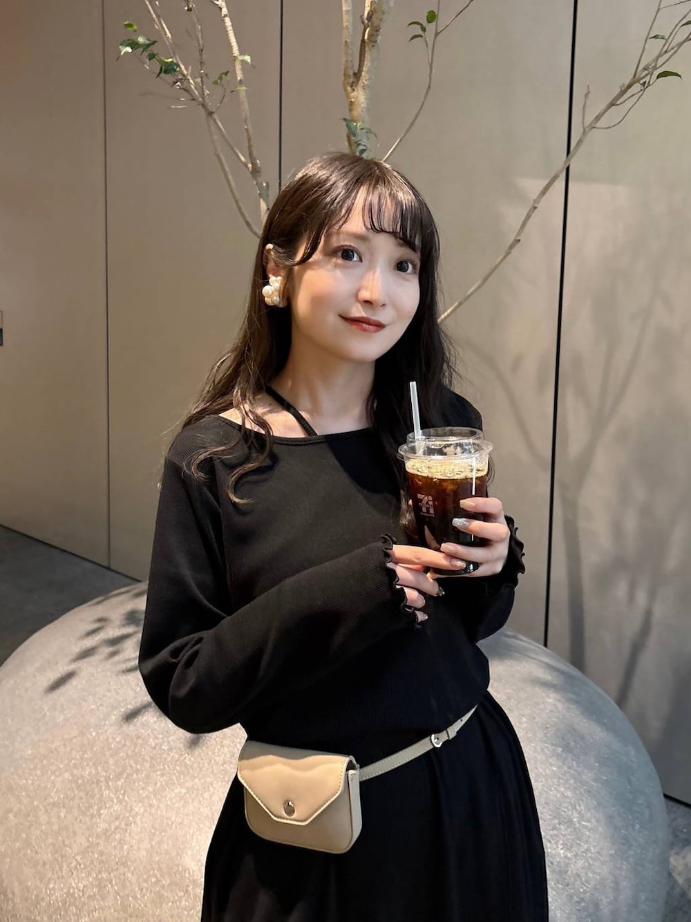 ブラック系のスカート、ベージュ系のボディバッグ/ウエストポーチ、ブラック系のパンプスを着用したレディースの春コーディネートの1枚目の写真