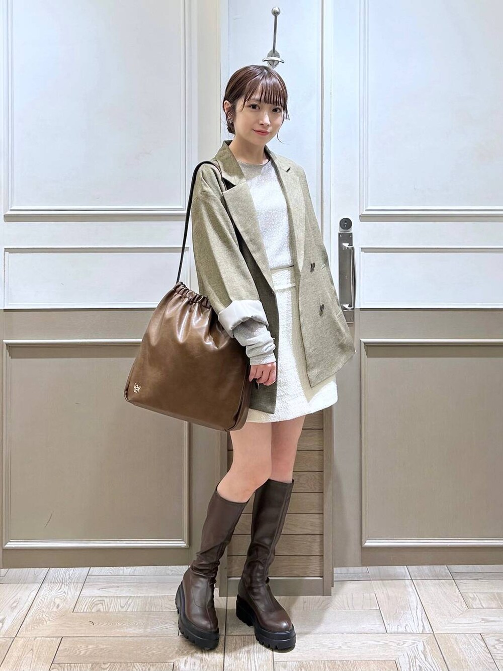 ブラウン系のテーラードジャケット、ブラウン系のブーツ、ホワイト系のTシャツ/カットソーを着用したレディースの秋コーディネートの1枚目の写真