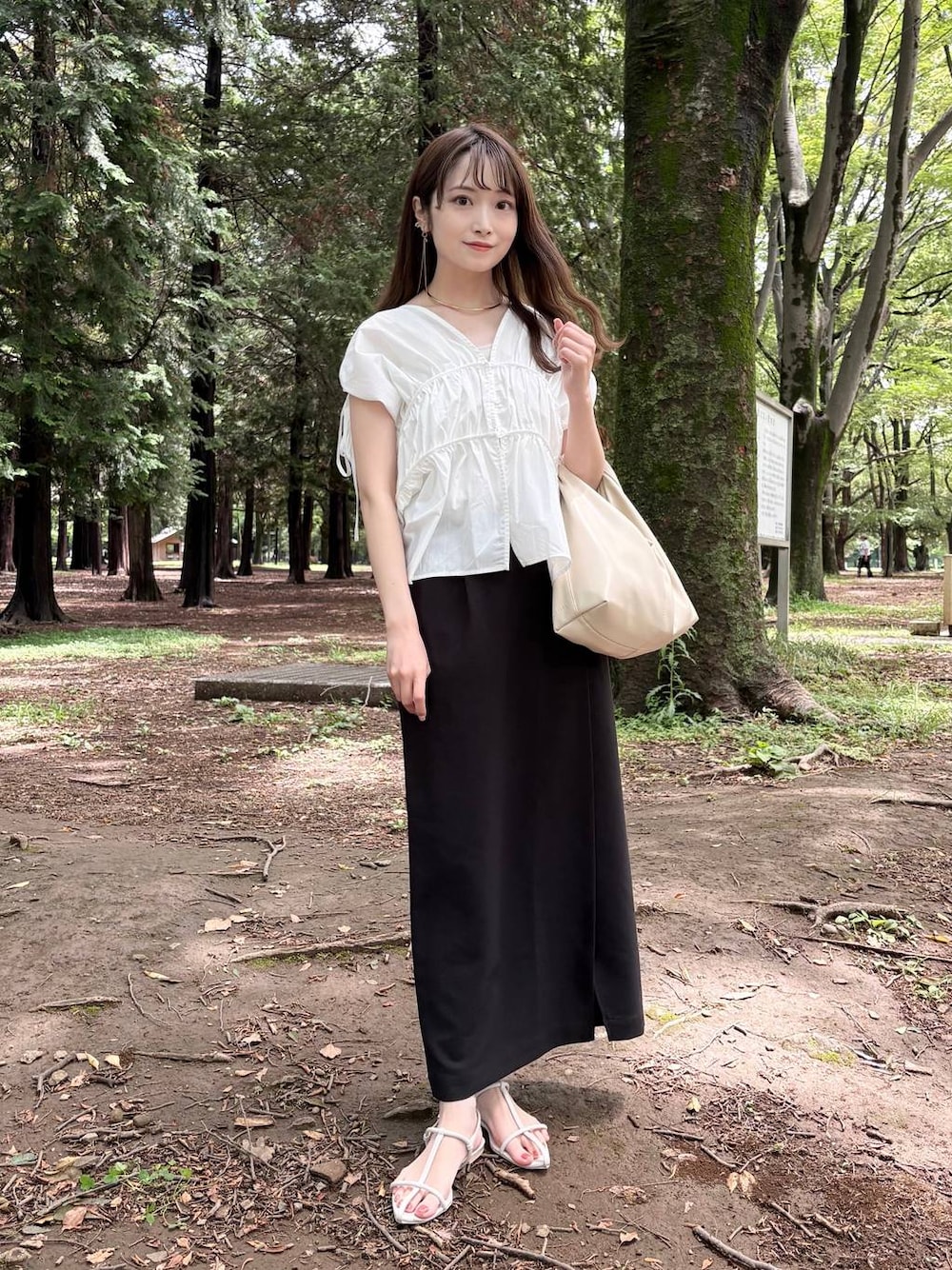 ホワイト系のTシャツ/カットソー、ホワイト系のサンダル、ブラック系のスカートを着用したレディースの夏コーディネートの1枚目の写真