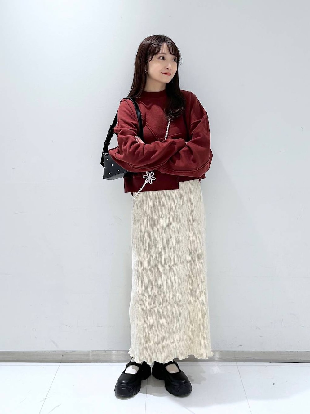 ブラック系のスニーカー、ホワイト系のスカート、ブラック系のショルダーバッグを着用したレディースの秋コーディネートの1枚目の写真