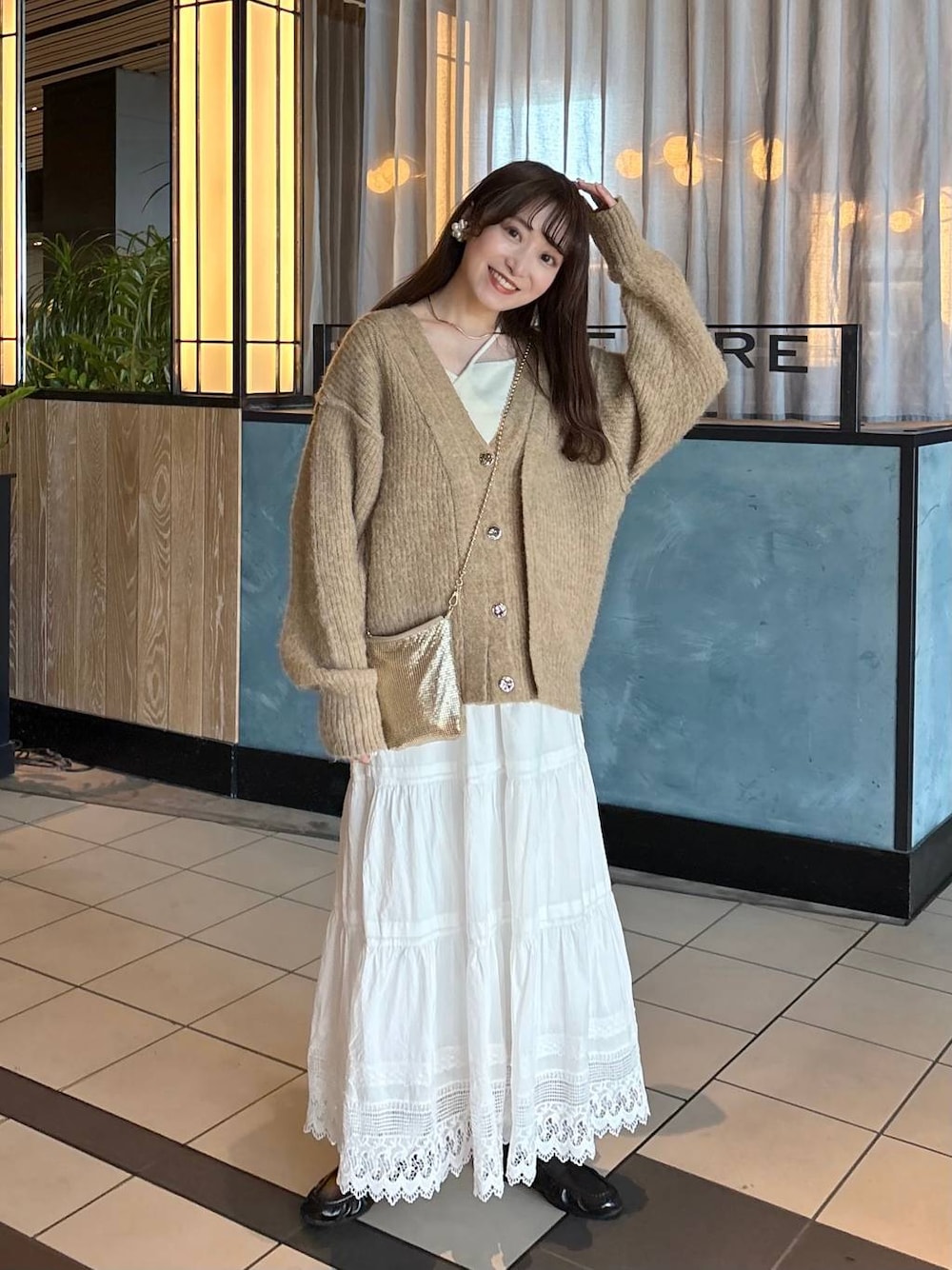 ゴールド系のショルダーバッグ、ブラウン系のローファー、ホワイト系のスカートを着用したレディースの春コーディネートの1枚目の写真