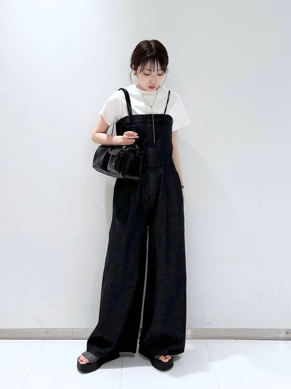 ブラック系のサンダル、ホワイト系のTシャツ/カットソー、ブラック系のボストンバッグを着用したレディースの夏コーディネートの1枚目の写真