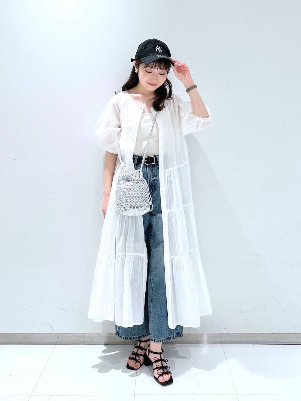 ホワイト系のTシャツ/カットソー、ブラック系のサンダル、ブルー系のデニムパンツを着用したレディースの春コーディネートの1枚目の写真