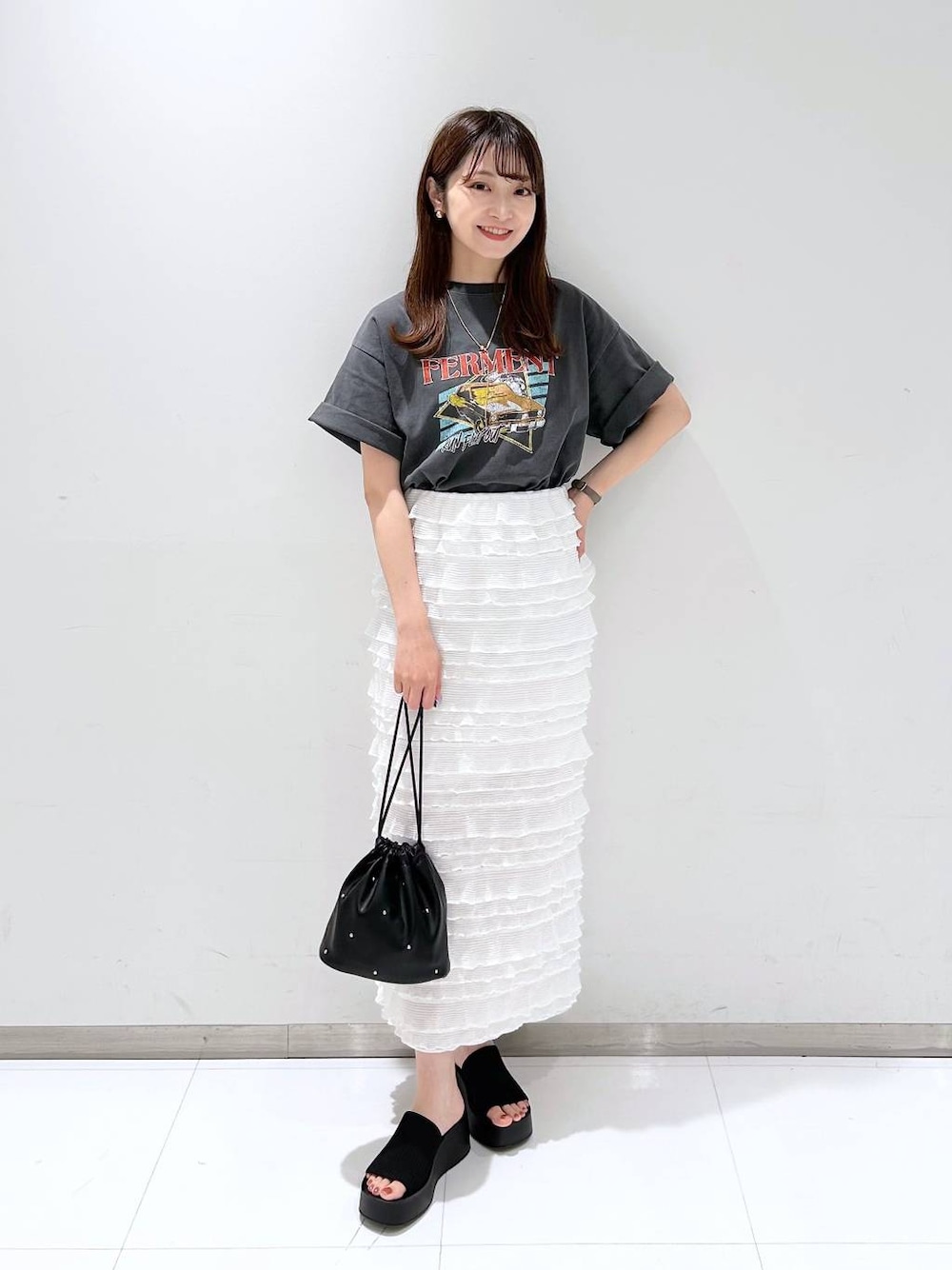 ブラック系のサンダル、ホワイト系のスカート、ブラック系のショルダーバッグを着用したレディースの夏コーディネートの1枚目の写真