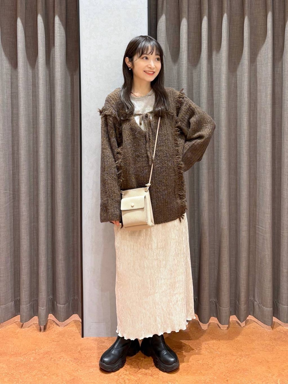 ブラウン系のニット/セーター、ホワイト系のTシャツ/カットソー、ブラック系のブーツを着用したレディースの冬コーディネートの1枚目の写真