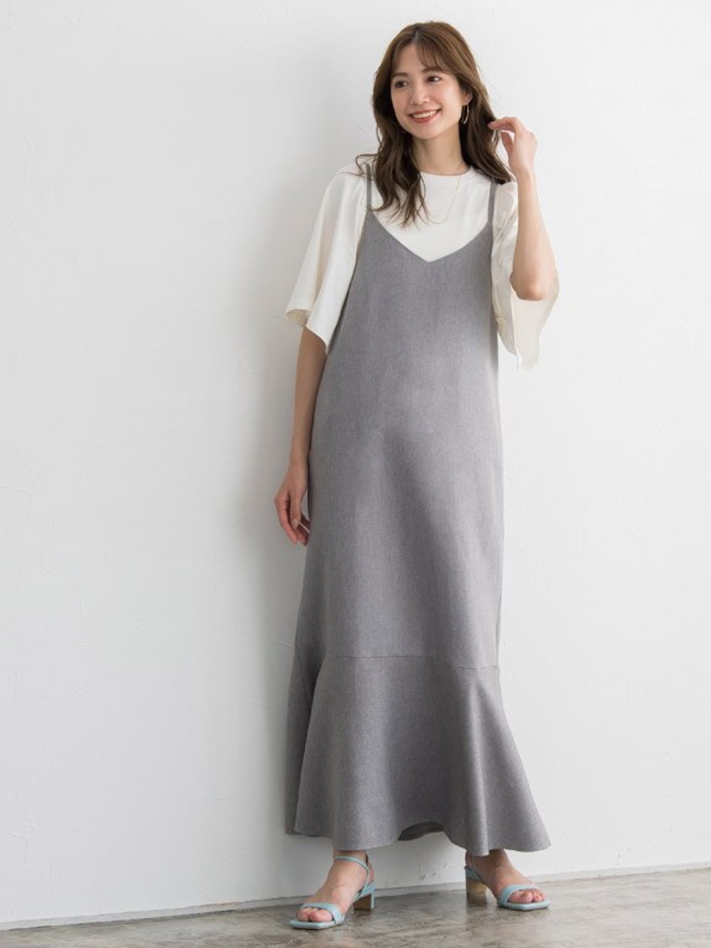 グレー系のジャンパースカート、ホワイト系のTシャツ/カットソー、ブルー系のサンダルを着用したレディースの春コーディネートの1枚目の写真