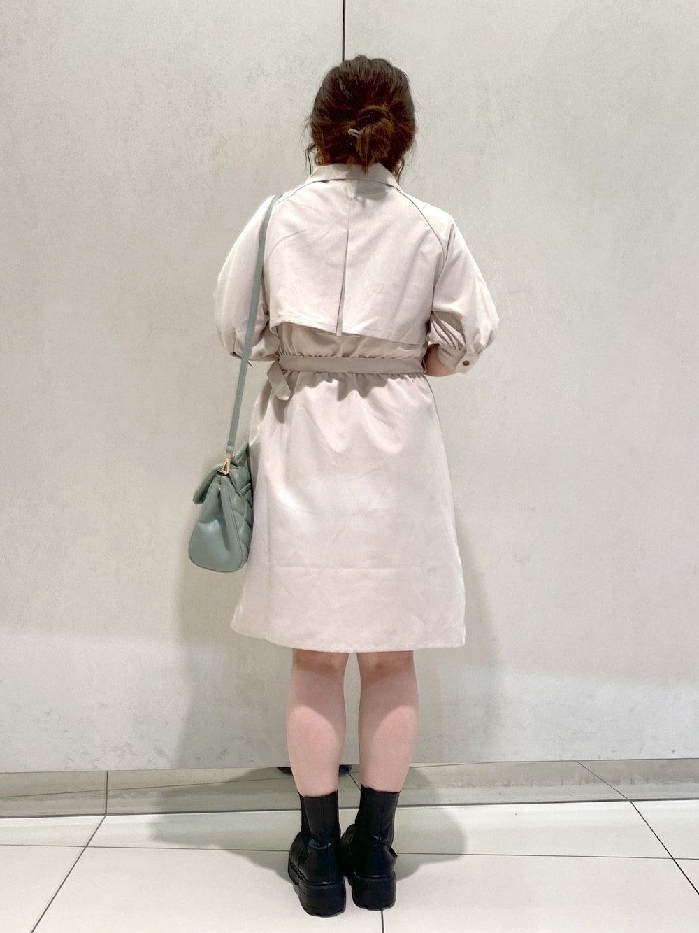 ベージュ系のワンピース、ブラック系のブーツ、グリーン系のショルダーバッグを着用したレディースの春コーディネートの3枚目の写真