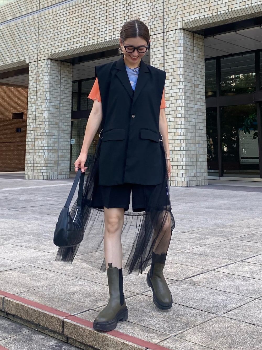 オレンジ系のTシャツ/カットソー、ブラック系のパンツ、グリーン系のブーツを着用したレディースの秋コーディネートの1枚目の写真