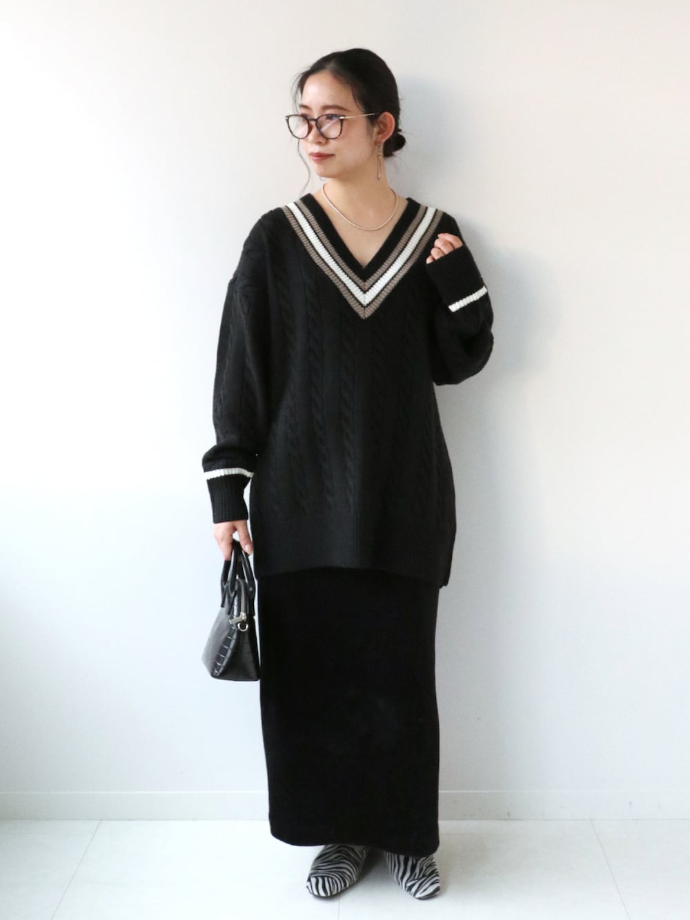 ブラック系のショルダーバッグ、ブラック系のスリッポン、ブラック系のスカートを着用したレディースの冬コーディネートの1枚目の写真