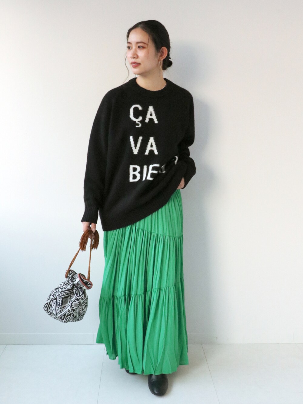 ブラック系のニット/セーター、グリーン系のスカート、ブラック系のショルダーバッグを着用したレディースの冬コーディネートの1枚目の写真