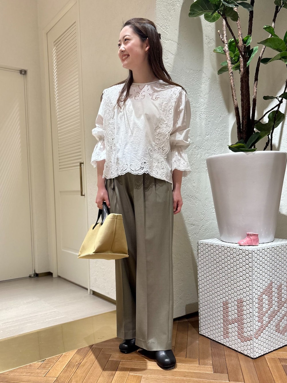 グリーン系のスラックス、ホワイト系のシャツ/ブラウス、ベージュ系のトートバッグを着用したレディースの春コーディネートの1枚目の写真