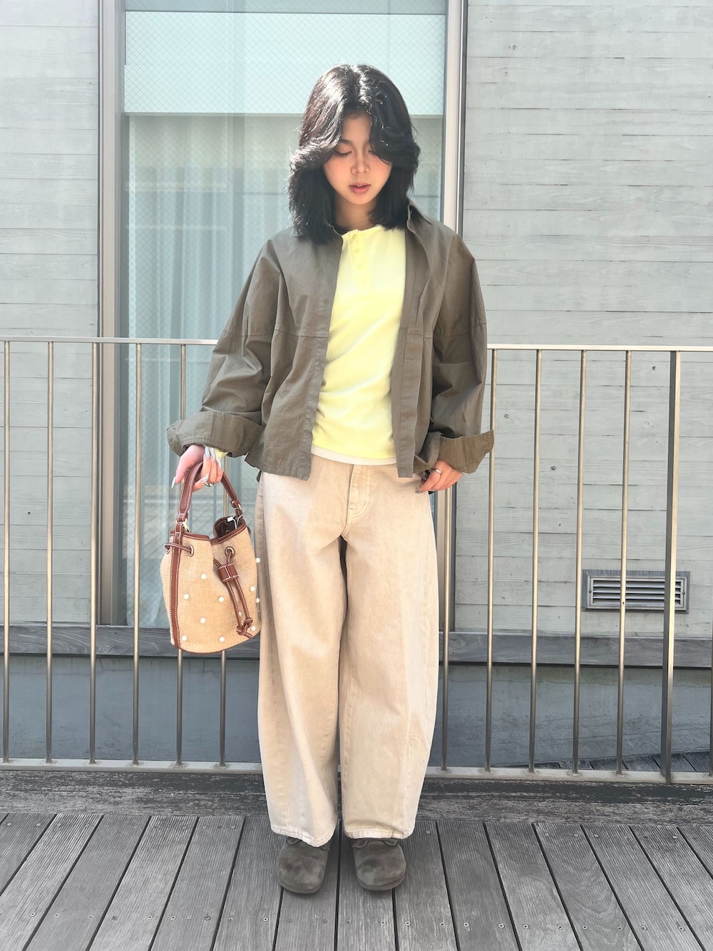 ベージュ系のデニムパンツ、グリーン系のシャツ/ブラウス、イエロー系のTシャツ/カットソーを着用したレディースの春コーディネートの1枚目の写真