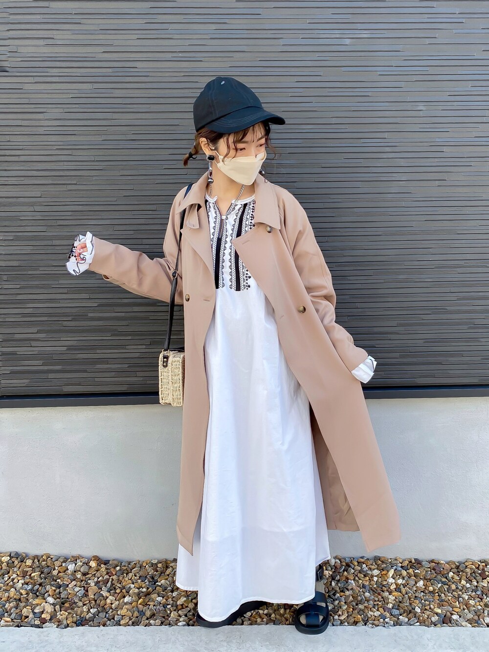 ベージュ系のトレンチコート、ホワイト系のワンピース、ブラック系のサンダルを着用したレディースの春コーディネートの1枚目の写真