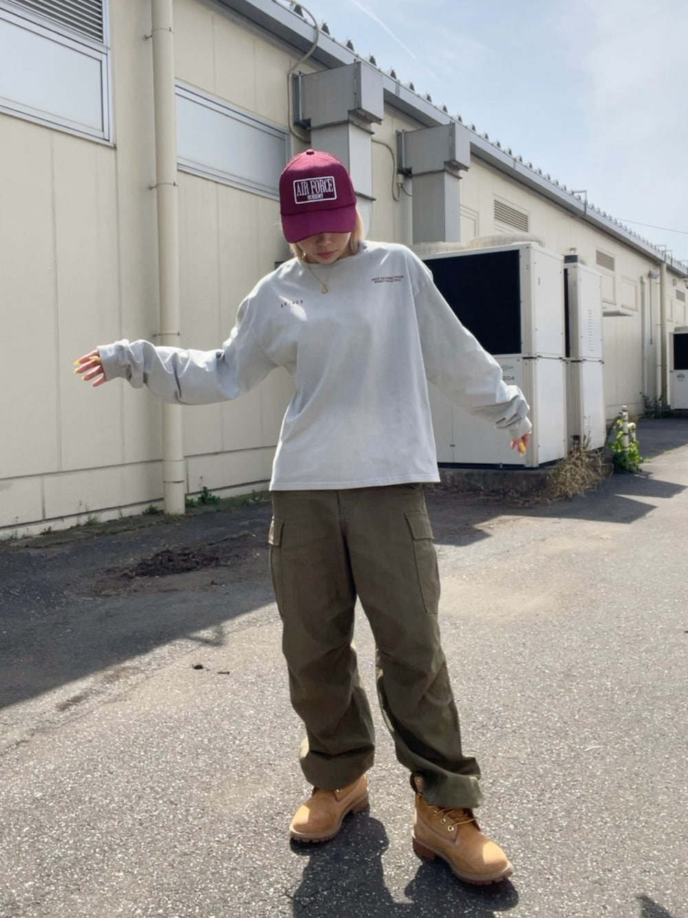 グレー系のTシャツ/カットソー、グリーン系のカーゴパンツ、レッド系のキャップを着用したレディースの春コーディネートの1枚目の写真