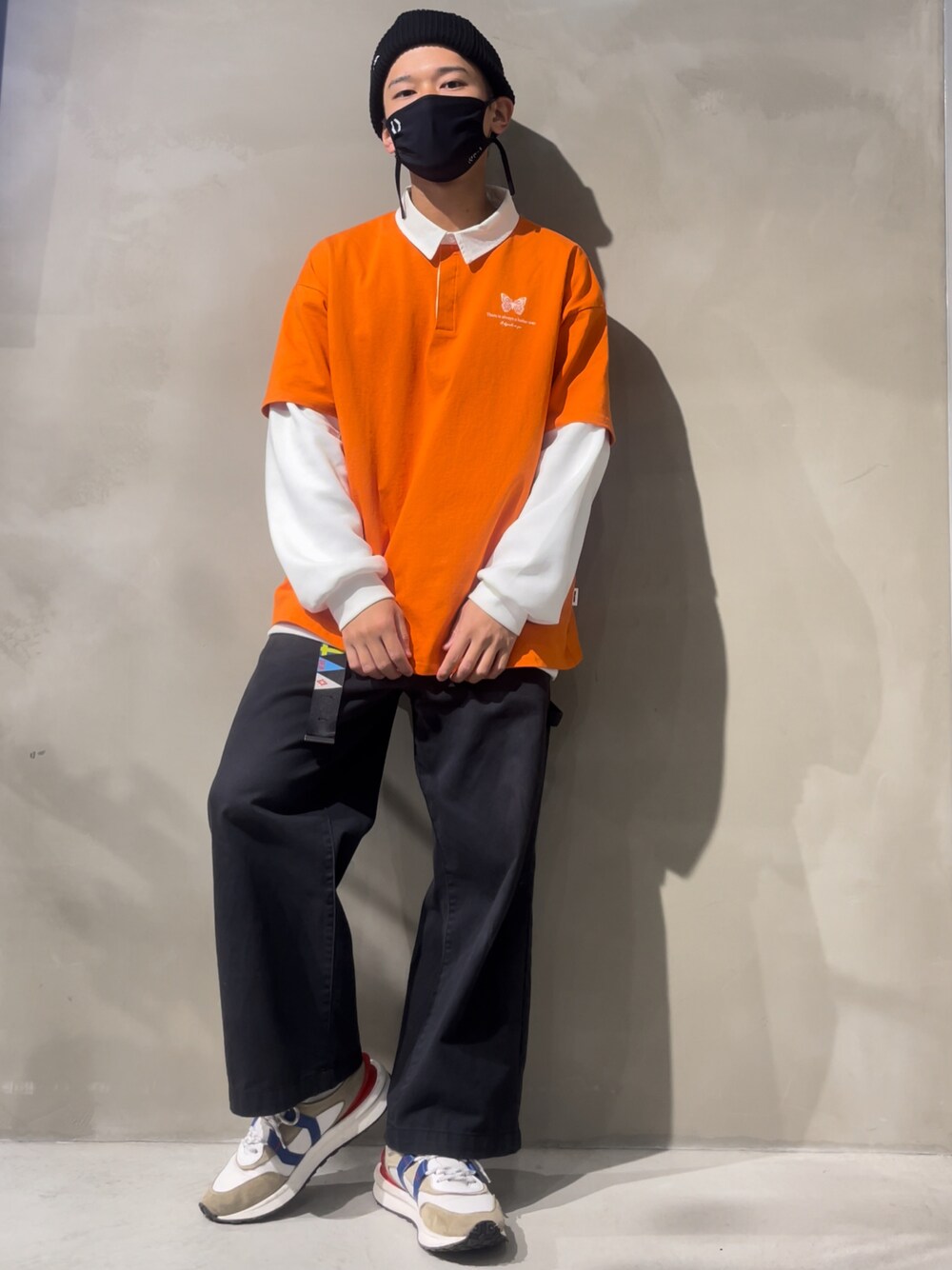 オレンジ系のTシャツ/カットソー、ホワイト系のトップス、ブラック系のチノパンツを着用したメンズの冬コーディネートの1枚目の写真