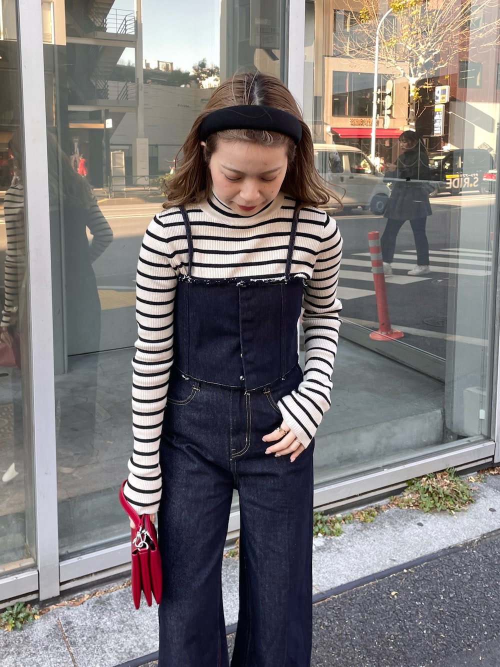 ブラック系のデニムパンツ、ホワイト系のニット/セーター、レッド系のショルダーバッグを着用したレディースの冬コーディネートの1枚目の写真