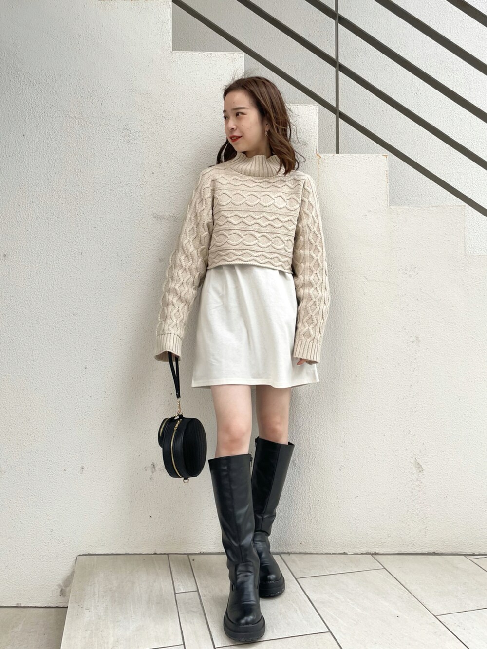 ホワイト系のニット/セーター、ブラック系のショルダーバッグ、ブラック系のブーツを着用したレディースの秋コーディネートの1枚目の写真