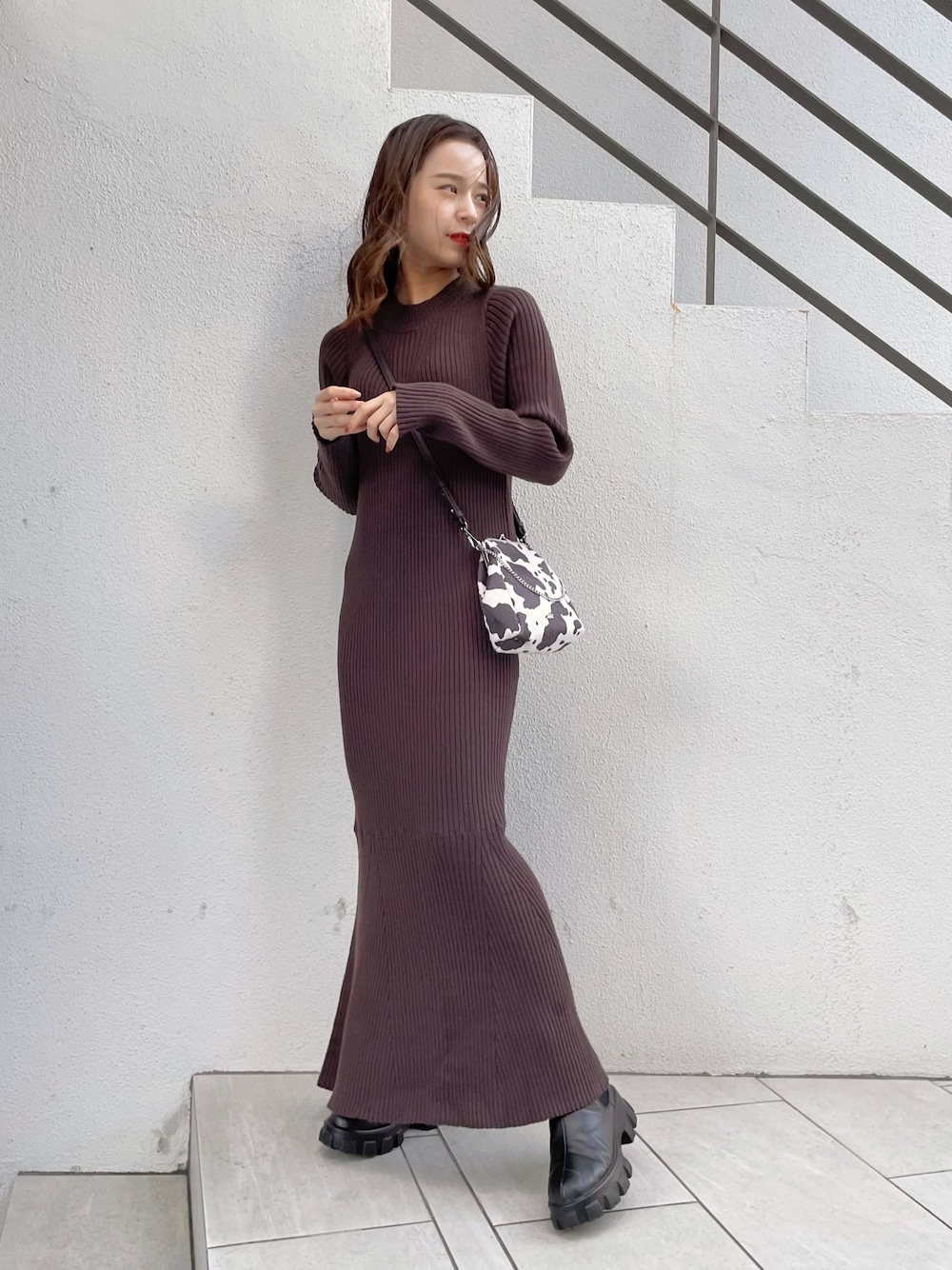 ブラウン系のショルダーバッグ、ブラウン系のワンピース、ブラック系のブーツを着用したレディースの秋コーディネートの1枚目の写真