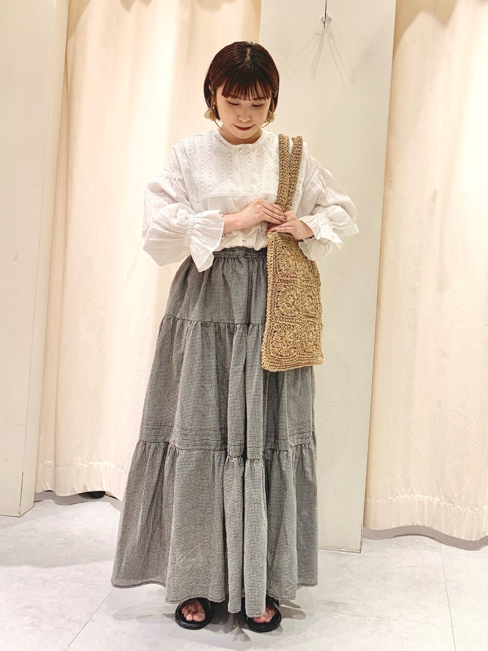 ベージュ系のハンドバッグ、ホワイト系のシャツ/ブラウス、ブラック系のサンダルを着用したレディースの春コーディネートの1枚目の写真