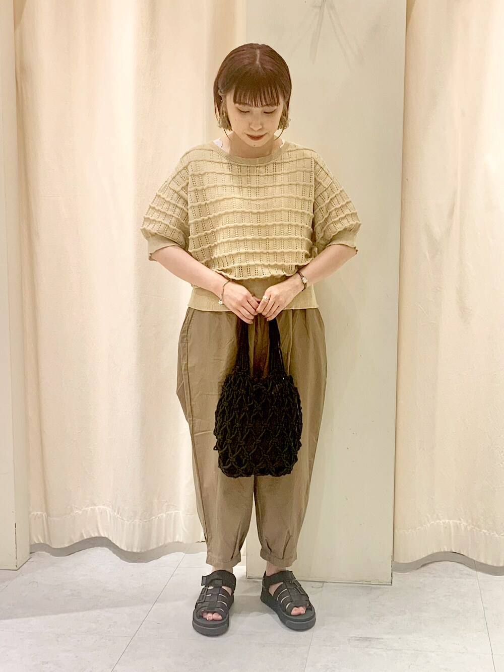 ベージュ系のカーディガン/ボレロ、ホワイト系のタンクトップ、ブラック系のハンドバッグを着用したレディースの夏コーディネートの1枚目の写真