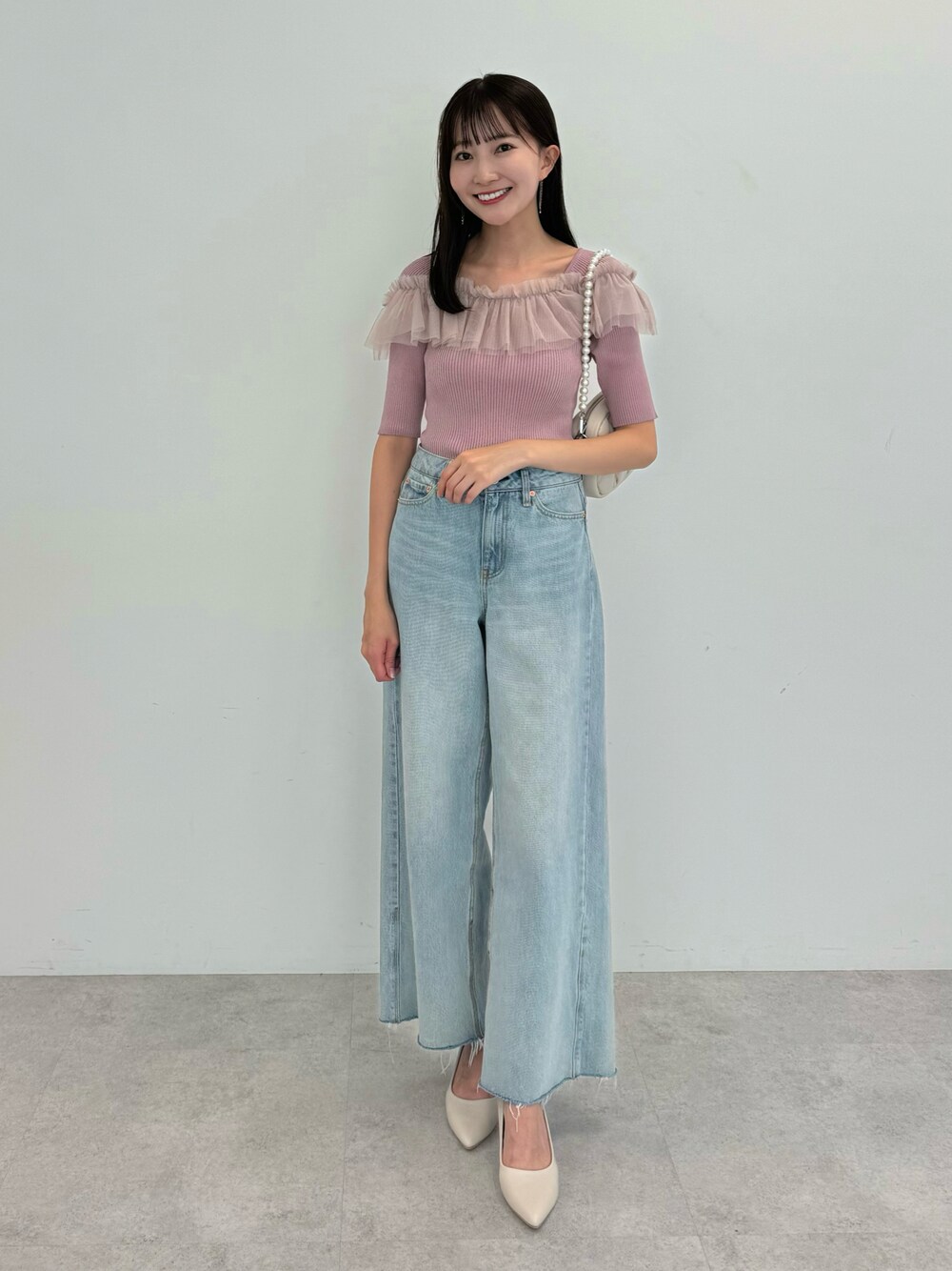 ブルー系のデニムパンツ、ピンク系のニット/セーター、ベージュ系のパンプスを着用したレディースの夏コーディネートの1枚目の写真