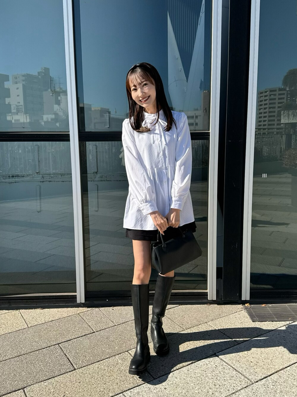 ホワイト系のチュニック、ブラック系のハンドバッグ、ブラック系のその他パンツを着用したレディースの冬コーディネートの1枚目の写真