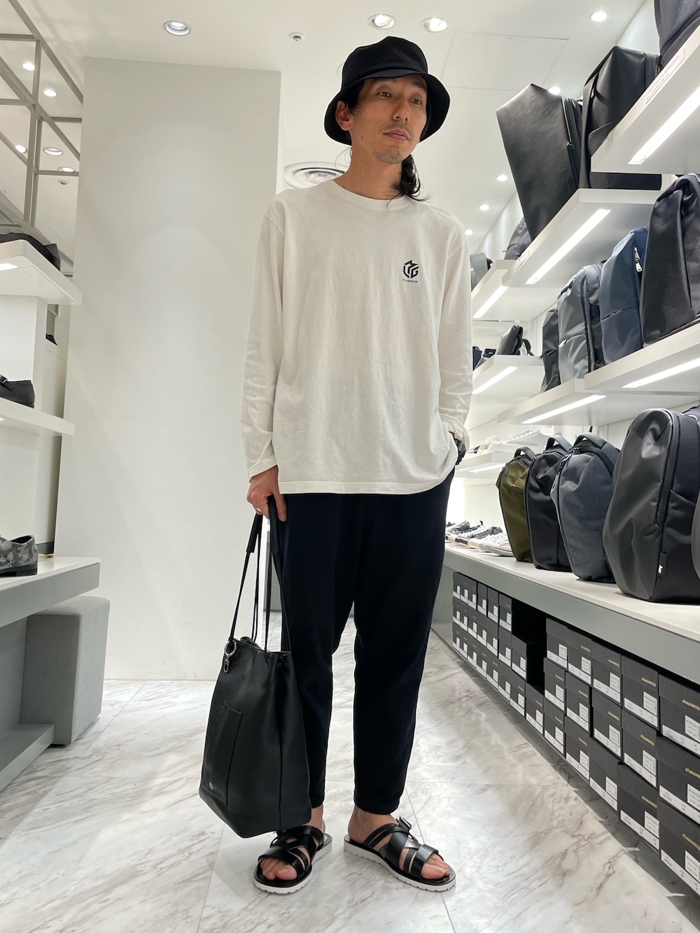 ブラック系のその他パンツ、ブラック系のサンダル、グレー系のトートバッグを着用したメンズの春コーディネートの1枚目の写真