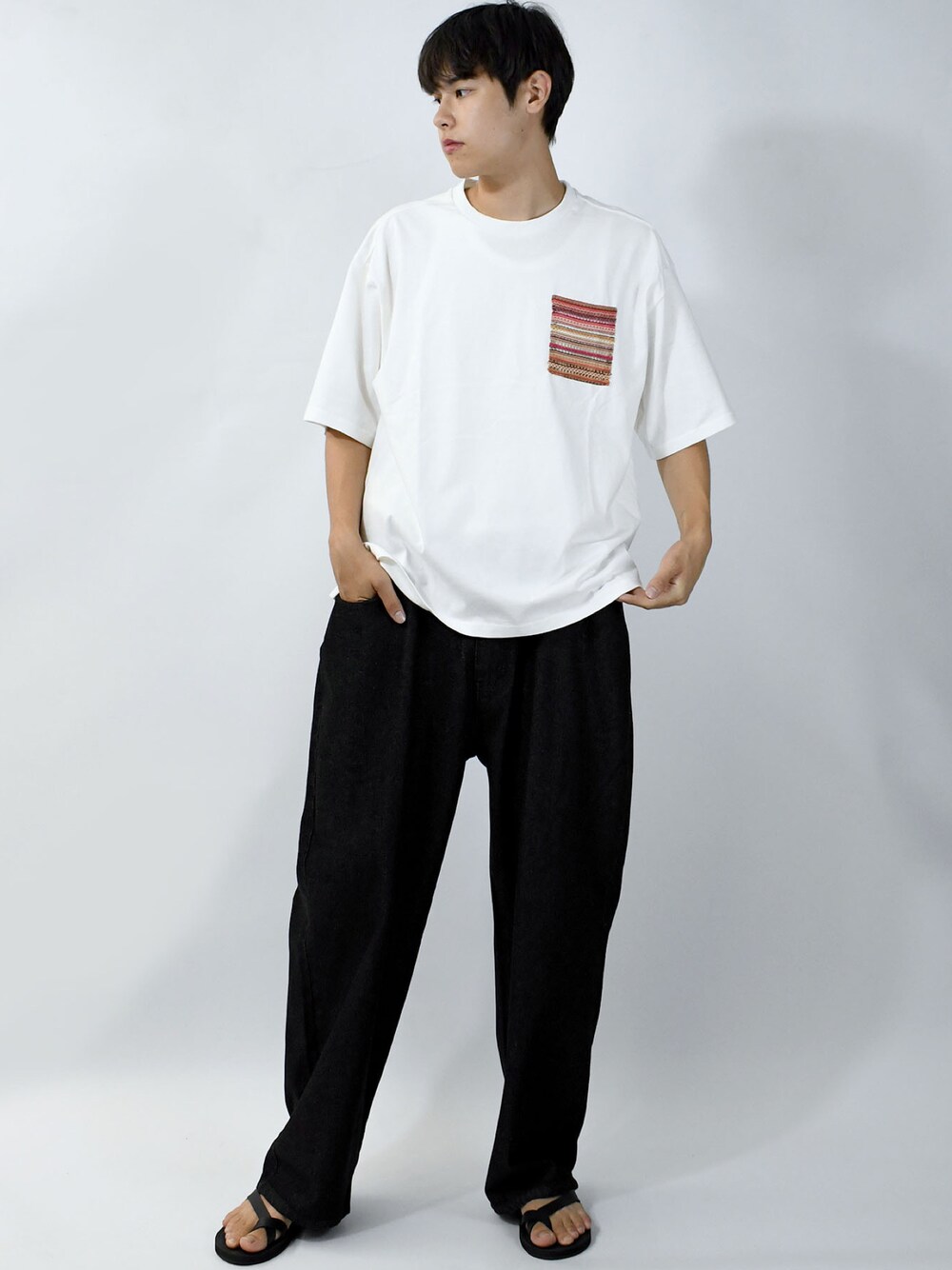 ホワイト系のTシャツ/カットソー、ブラック系のデニムパンツ、ブラック系のサンダルを着用したメンズの夏コーディネートの1枚目の写真