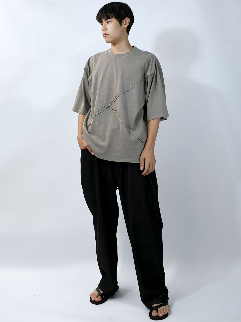ブラウン系のTシャツ/カットソー、ブラック系のスラックス、ブラック系のサンダルを着用したメンズの夏コーディネートの1枚目の写真