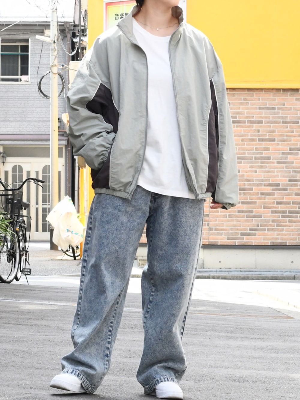 グレー系のナイロンジャケット、ブルー系のデニムパンツを着用したメンズの秋コーディネートの1枚目の写真
