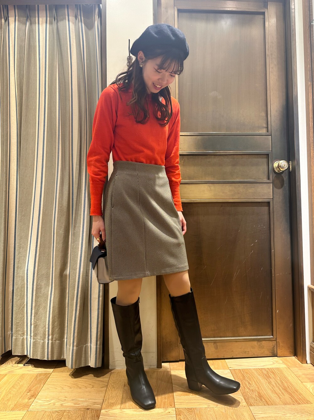 レッド系のニット/セーター、ブラウン系のスカートを着用したレディースの冬コーディネートの1枚目の写真