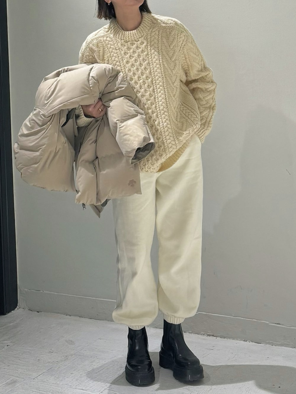 ベージュ系のダウンジャケット/コート、ホワイト系のスウェットパンツ、ブラック系のブーツを着用したレディースの冬コーディネートの1枚目の写真