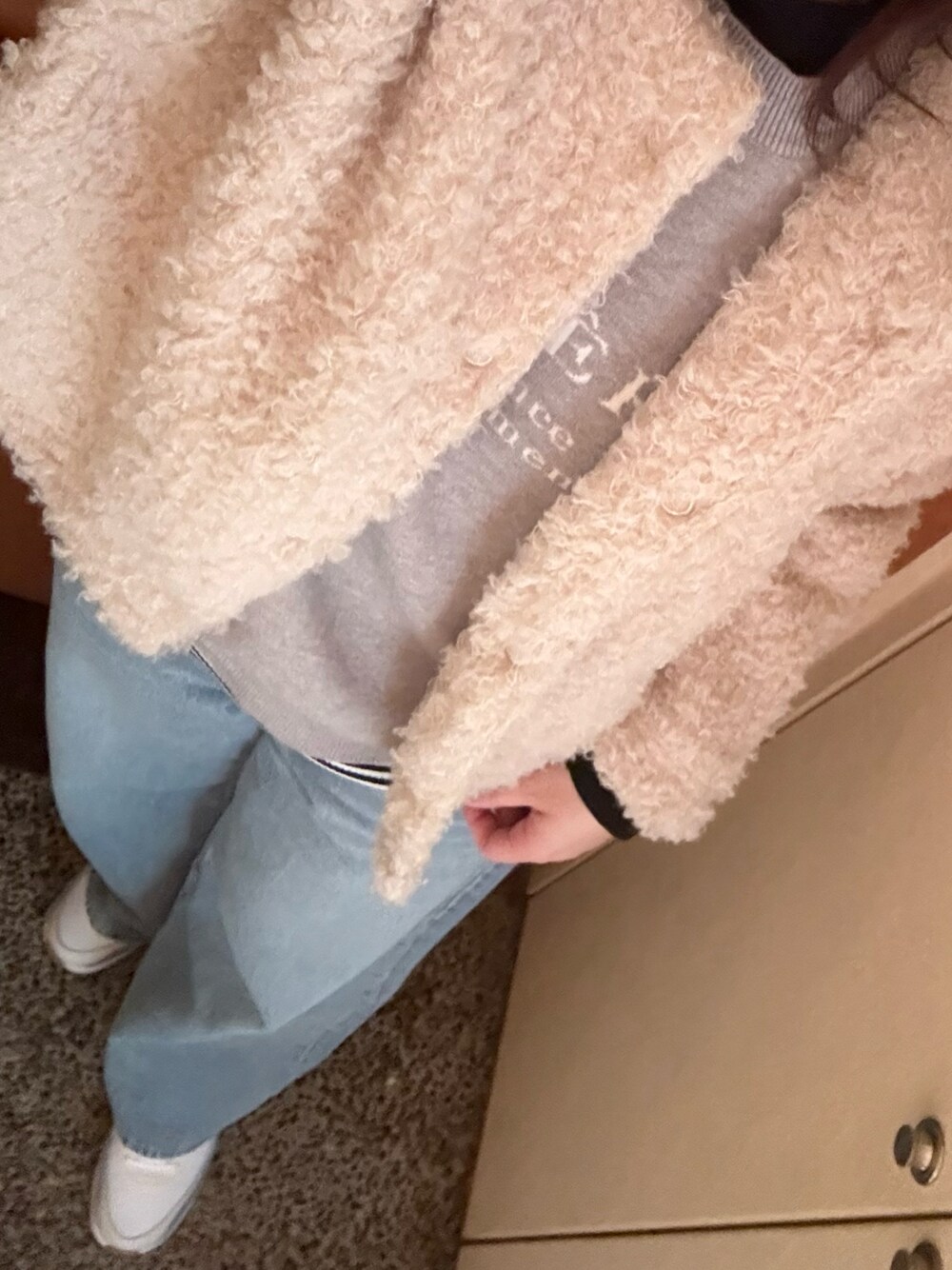 ホワイト系のノーカラージャケット、ブラック系のTシャツ/カットソー、ブルー系のデニムパンツを着用したレディースの冬コーディネートの1枚目の写真