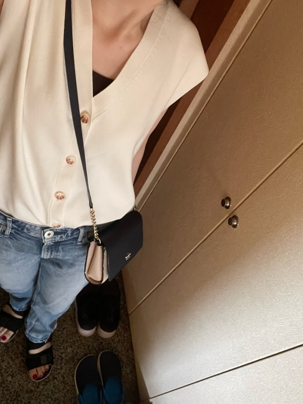 ホワイト系のベスト、ブルー系のデニムパンツ、ブラック系のサンダルを着用したレディースの夏コーディネートの1枚目の写真