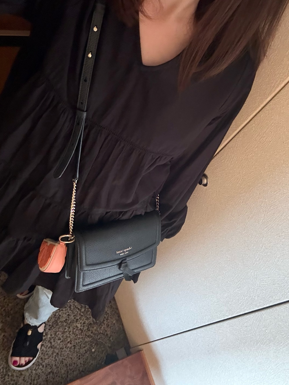 ブラック系のワンピース、ブルー系のデニムパンツ、ブラック系のショルダーバッグを着用したレディースの春コーディネートの1枚目の写真