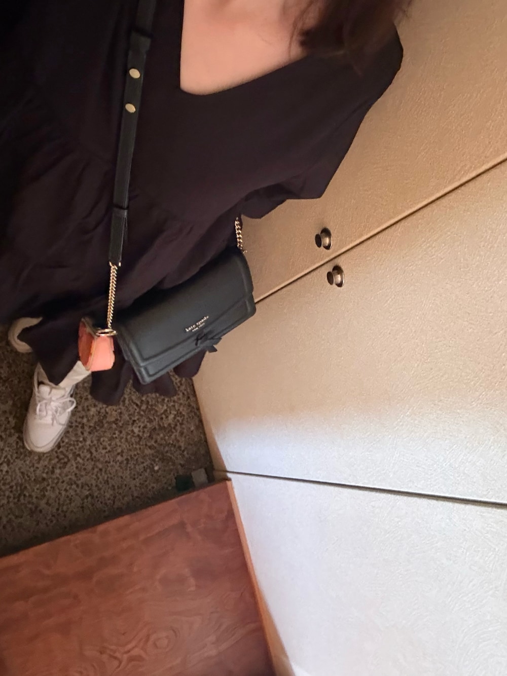 ブラック系のワンピース、ベージュ系のデニムパンツ、ブラック系のショルダーバッグを着用したレディースの春コーディネートの1枚目の写真