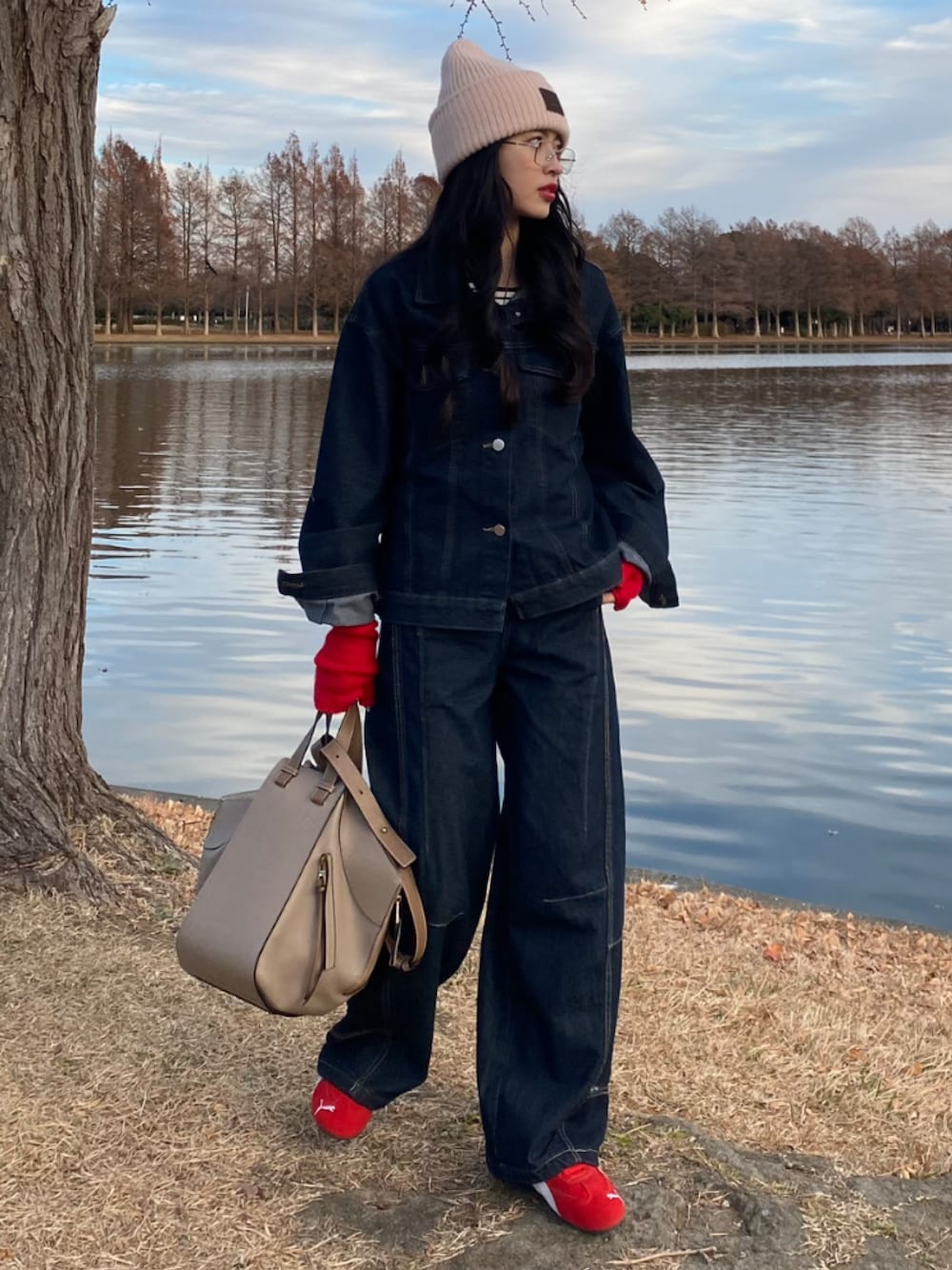 ベージュ系のハンドバッグ、レッド系のスニーカーを着用したレディースの秋コーディネートの1枚目の写真